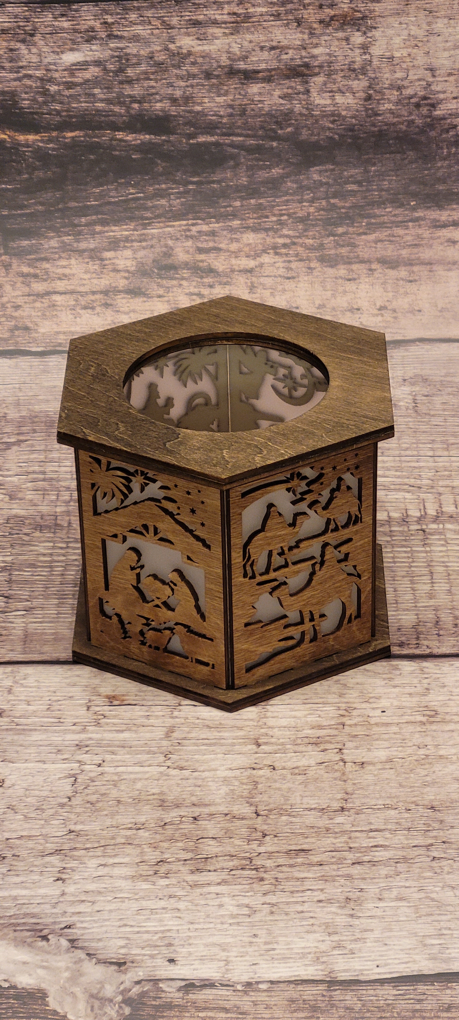 Side angle of handcrafted wood nativity lantern showing hexagonal shape and candle holder opening