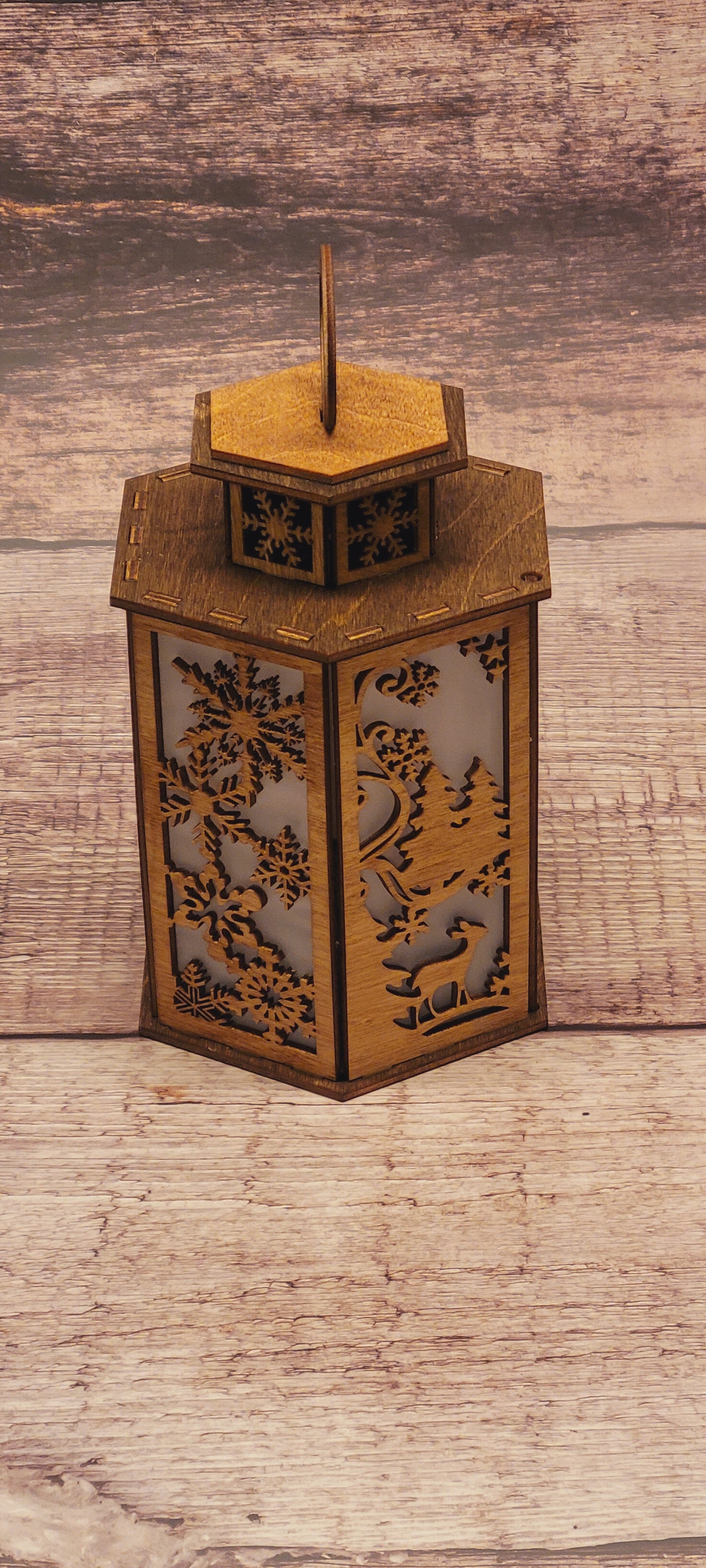 Front view of tiered Christmas candle holder showing layered winter landscape and snowflake cutouts