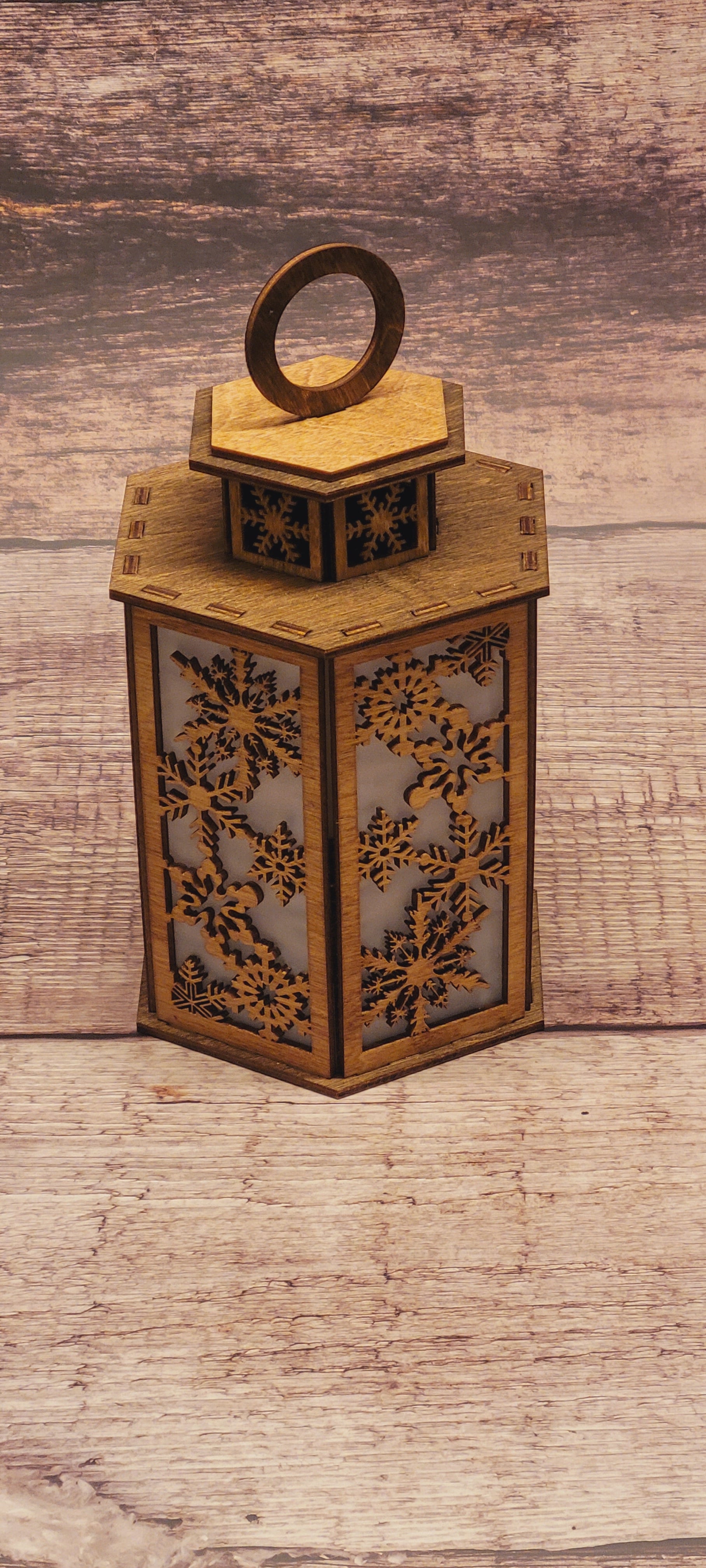 Tiered laser-cut wood Christmas lantern with winter scene and snowflake details in natural wood finish