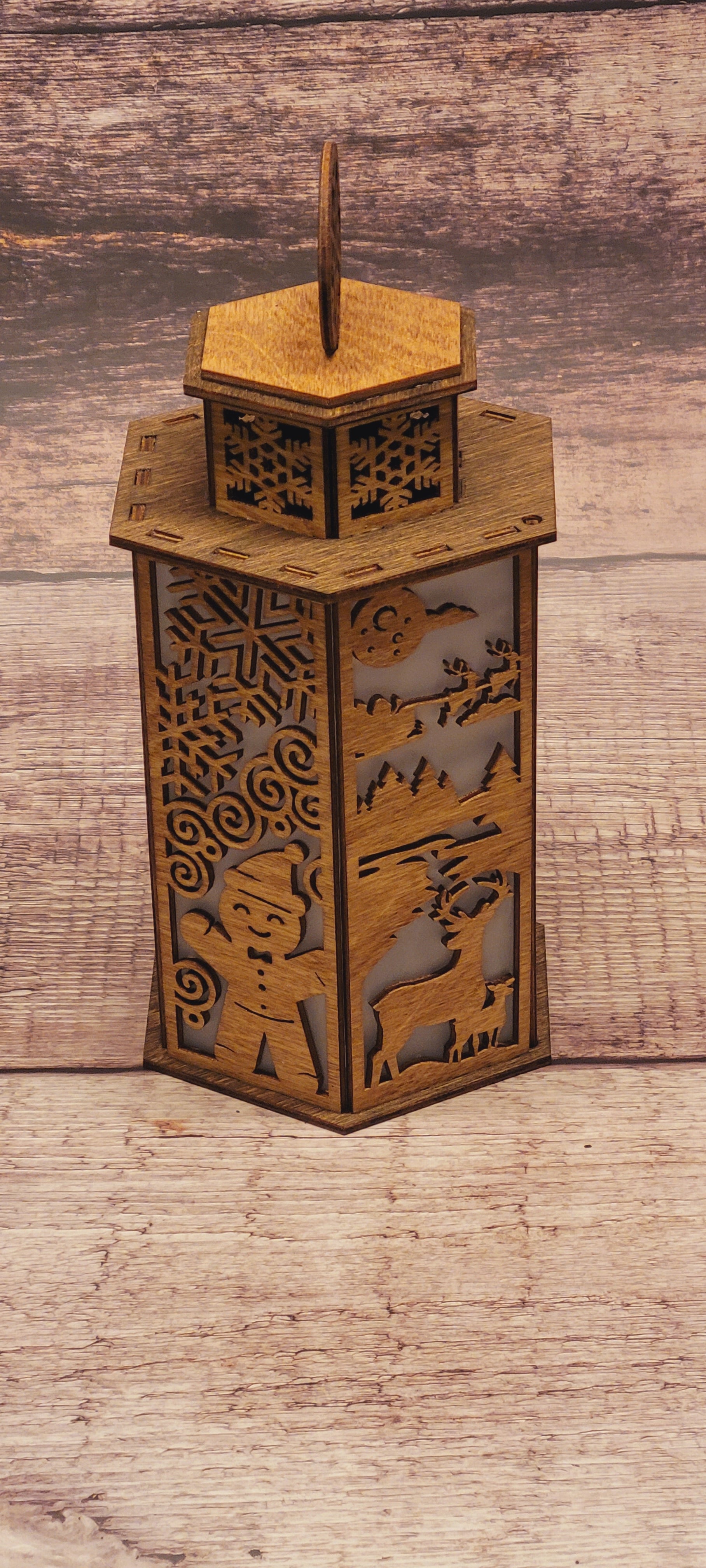 Front view of wood Christmas lantern featuring intricate snowflake handle and holiday cutout design