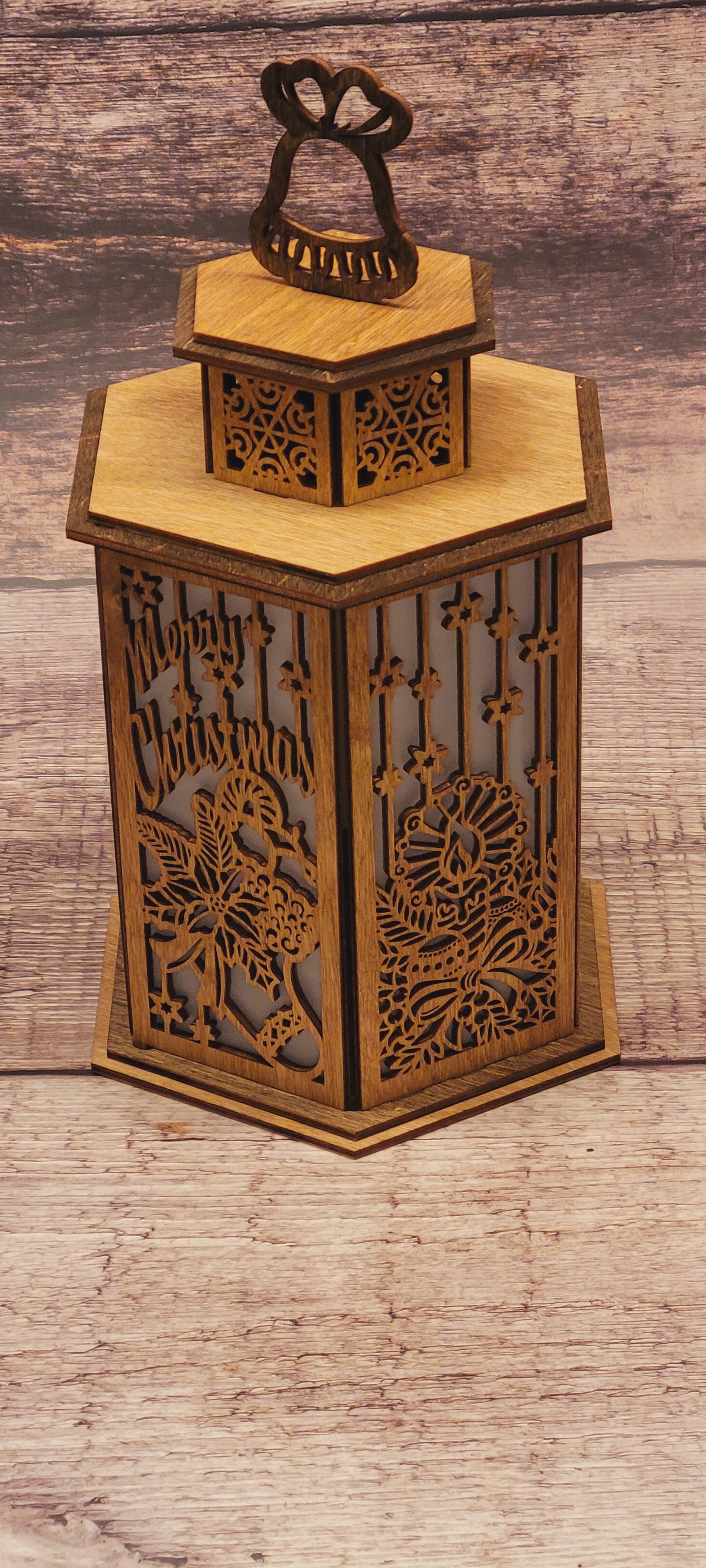 Close-up of Christmas lantern with bell handle showing precision laser-cut details and artisan craftsmanship
