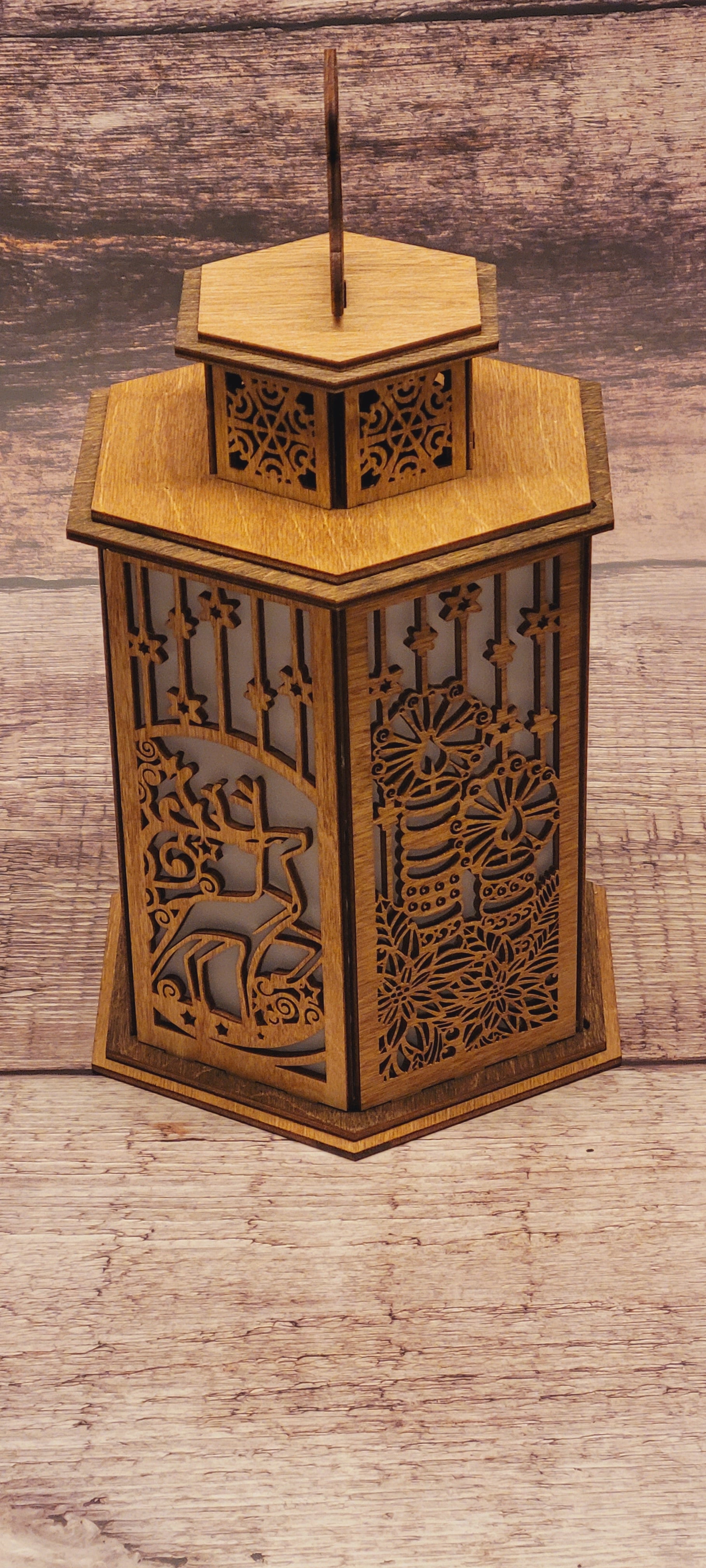 Handcrafted Christmas lantern in laser-cut wood with decorative bell handle and natural wood grain
