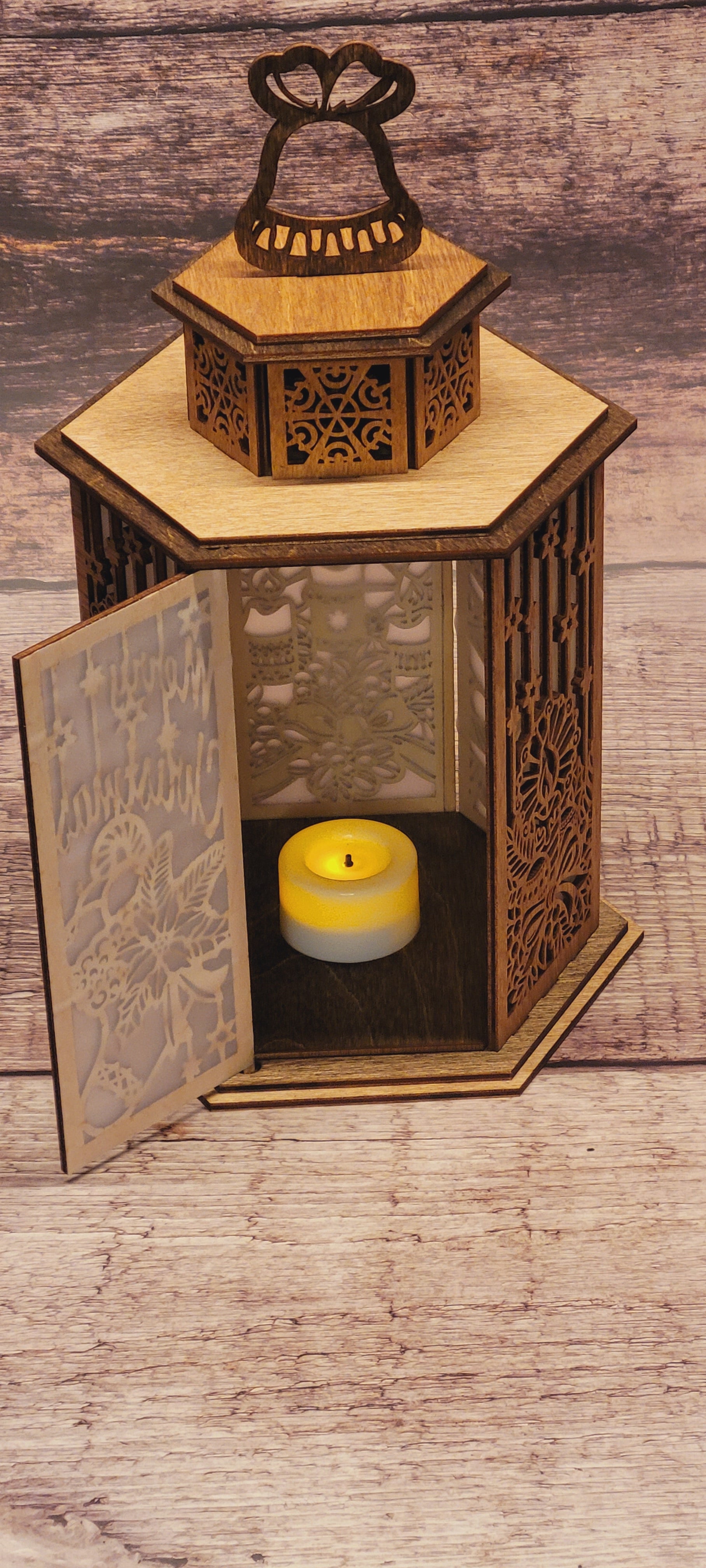 Side angle of handcrafted wood Christmas lantern with bell handle and candle holder opening
