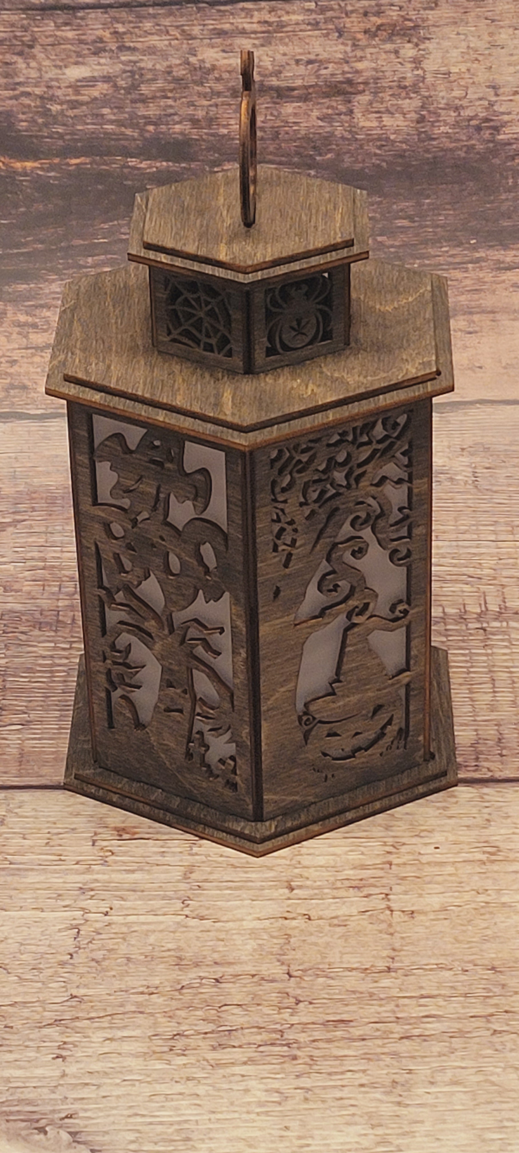 Handcrafted Halloween lantern in laser-cut wood with decorative pumpkin handle and natural finish
