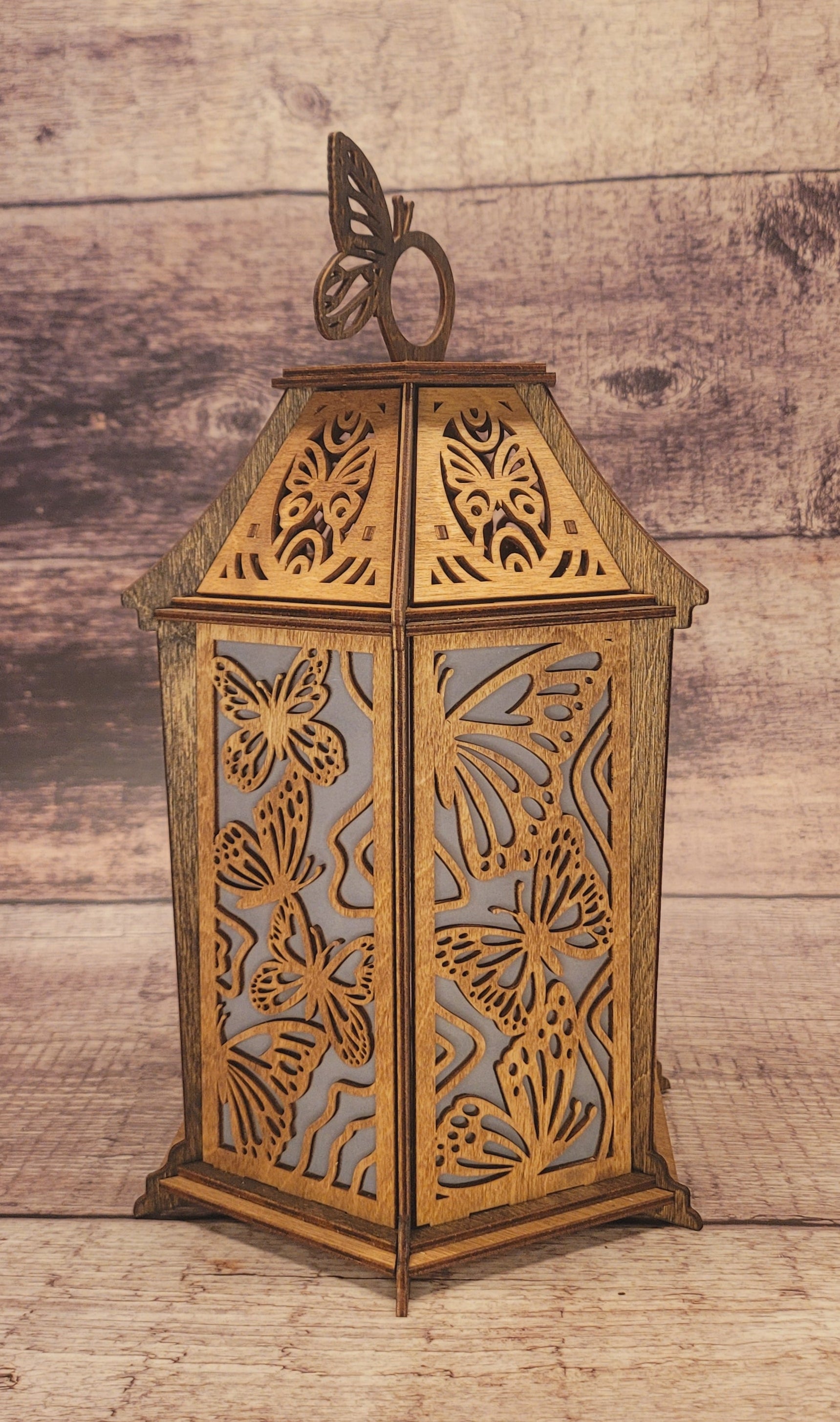 Front view of butterfly-shaped wood lantern showing delicate laser-cut patterns and candle opening