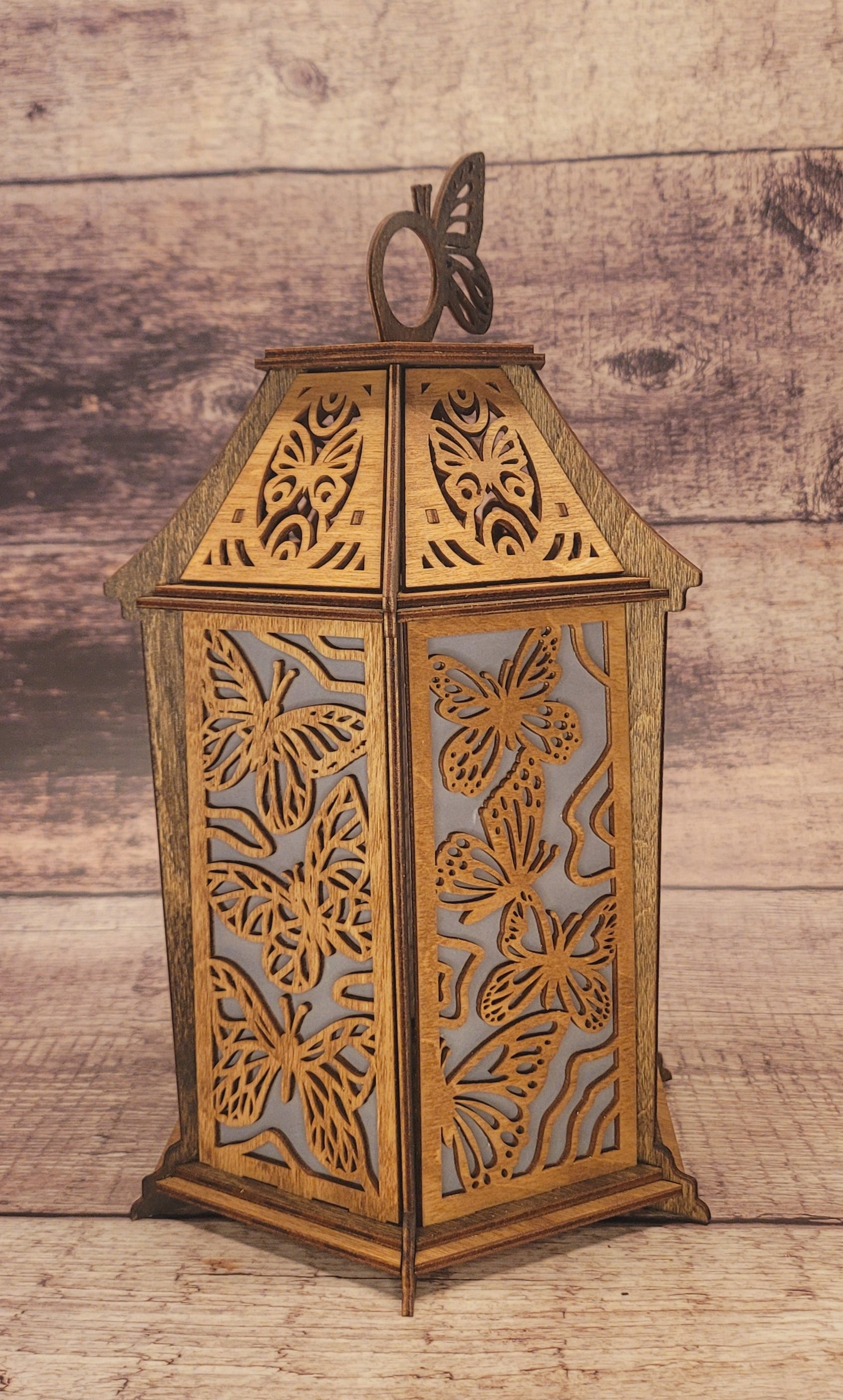 Handcrafted butterfly lantern in laser-cut wood with intricate wing details and natural grain finish