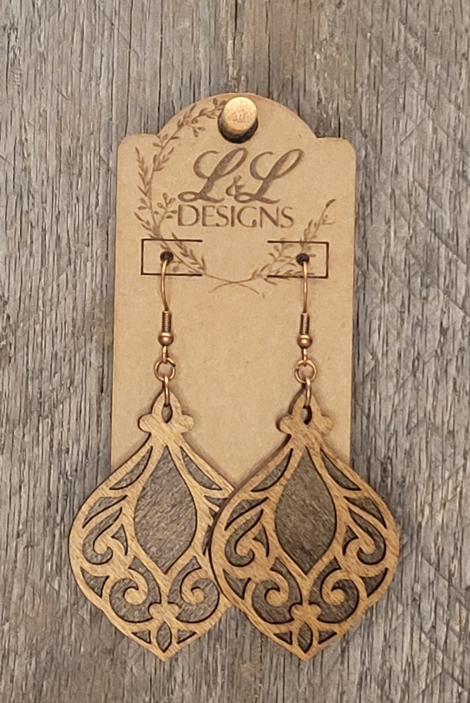 Elegant laser-cut wood earrings with ornate filigree design and natural grain finish