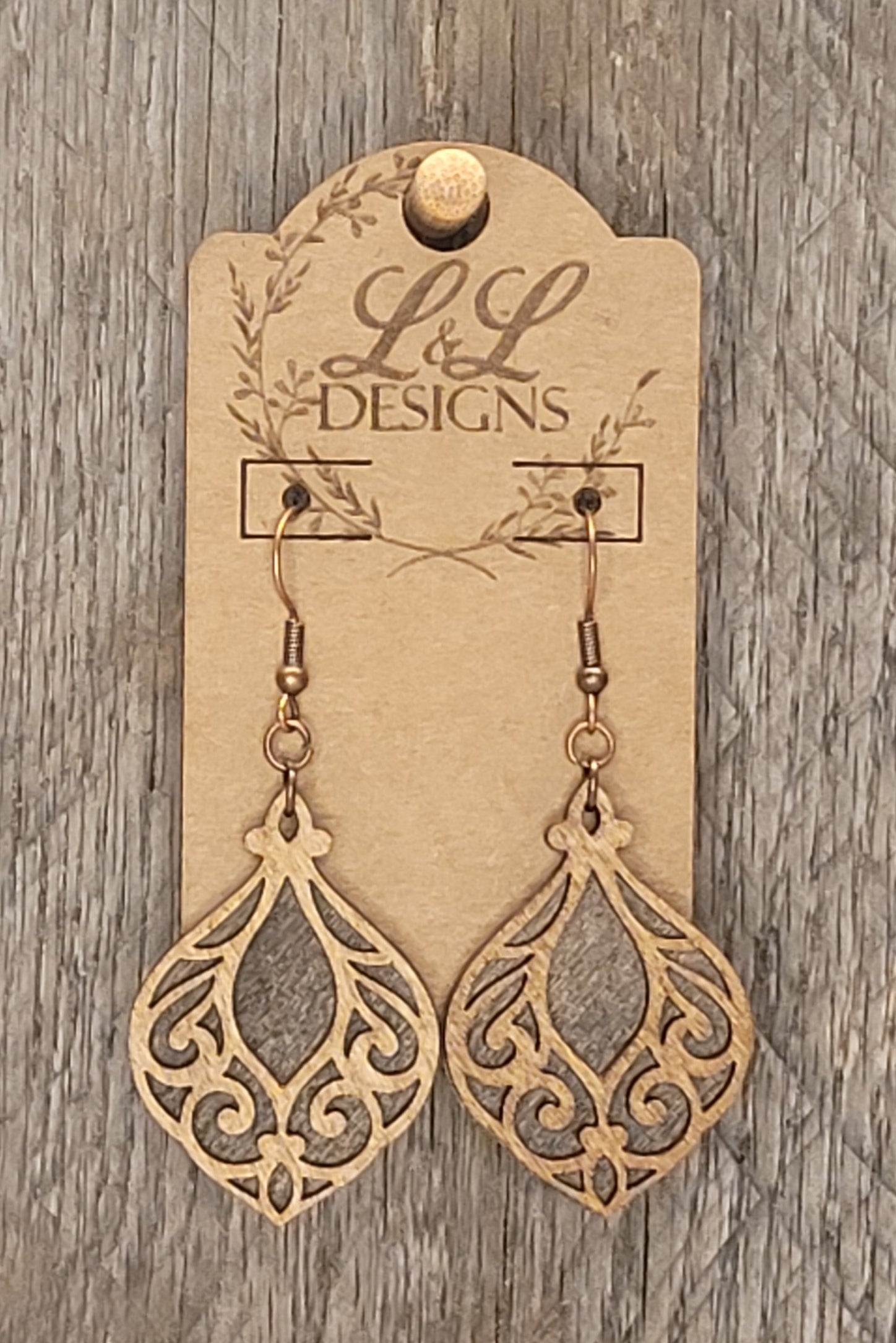 Close-up of handcrafted wood earrings showing intricate filigree pattern and lightweight design