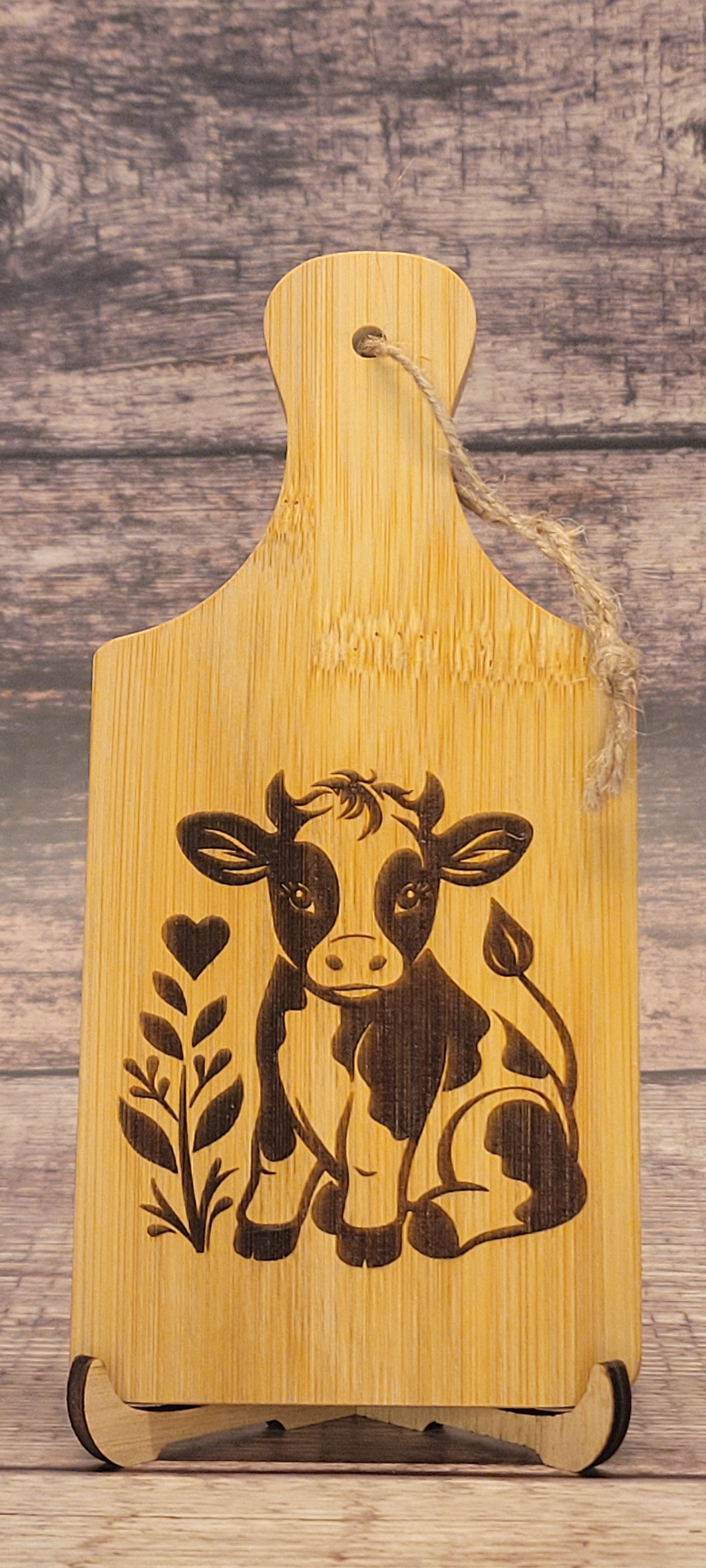 Small bamboo charcuterie board with laser-engraved cow design and natural finish