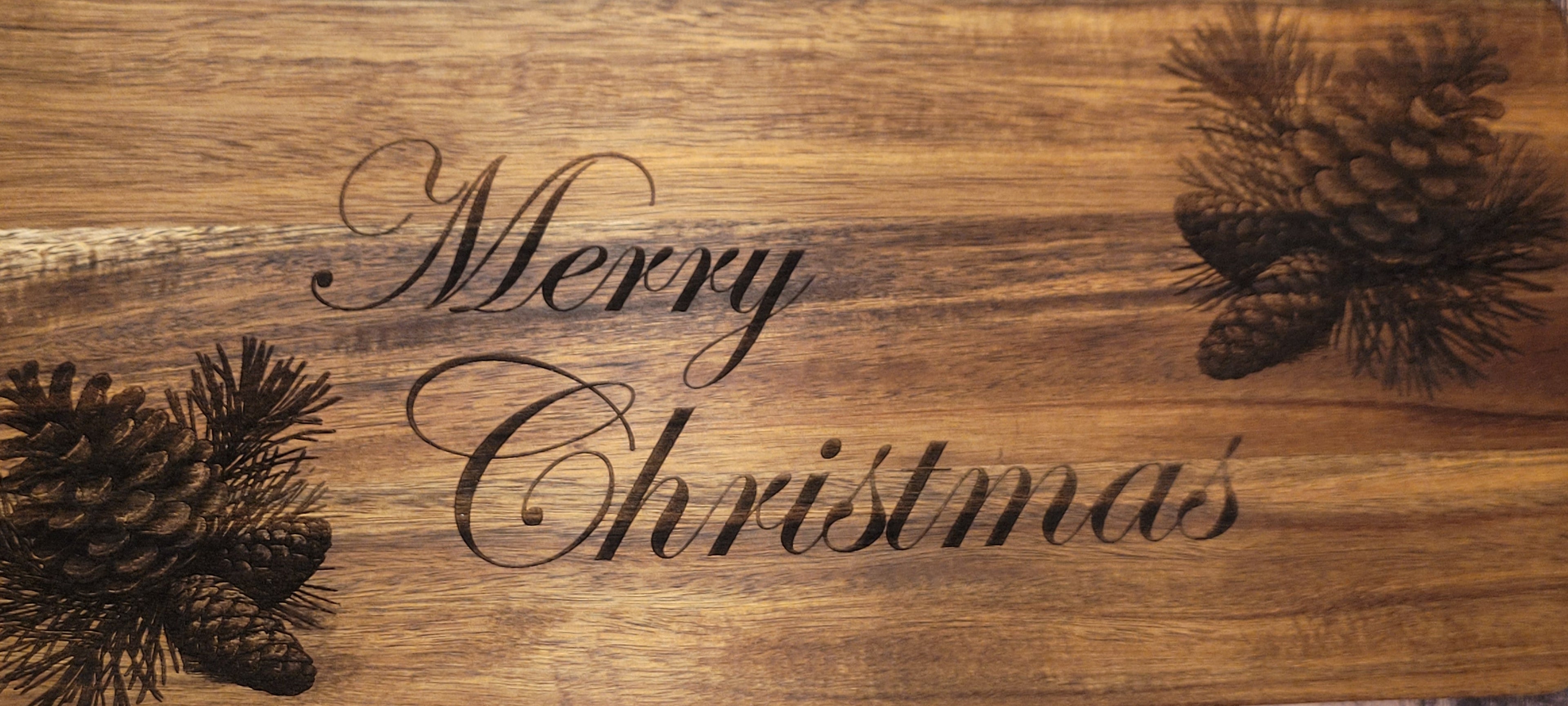 Wood serving board with laser-engraved 'Merry Christmas' and pinecone design