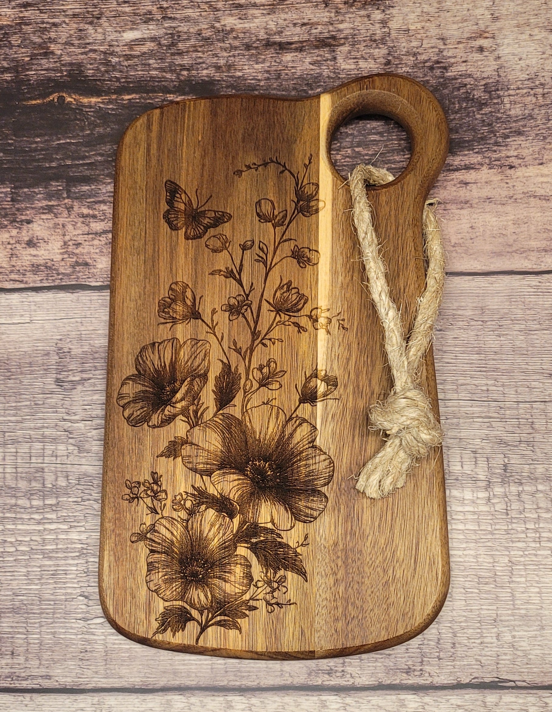 Wood serving board with laser-engraved butterfly and wildflower design and circle handle