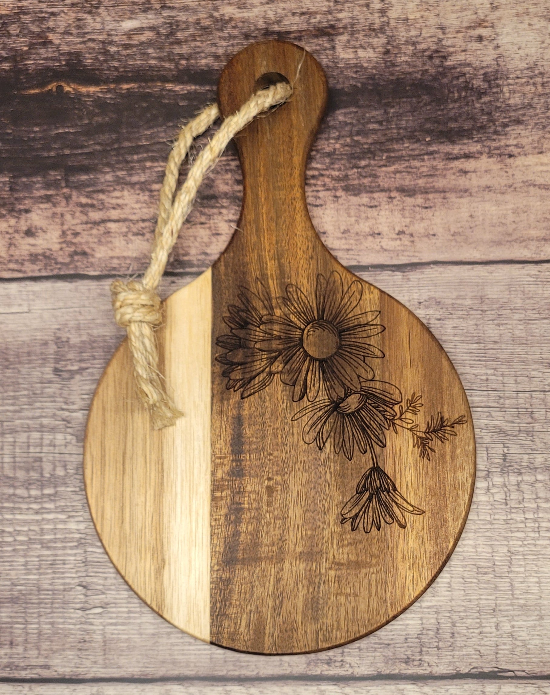 Round wood serving board with laser-engraved daisy flower design and natural finish