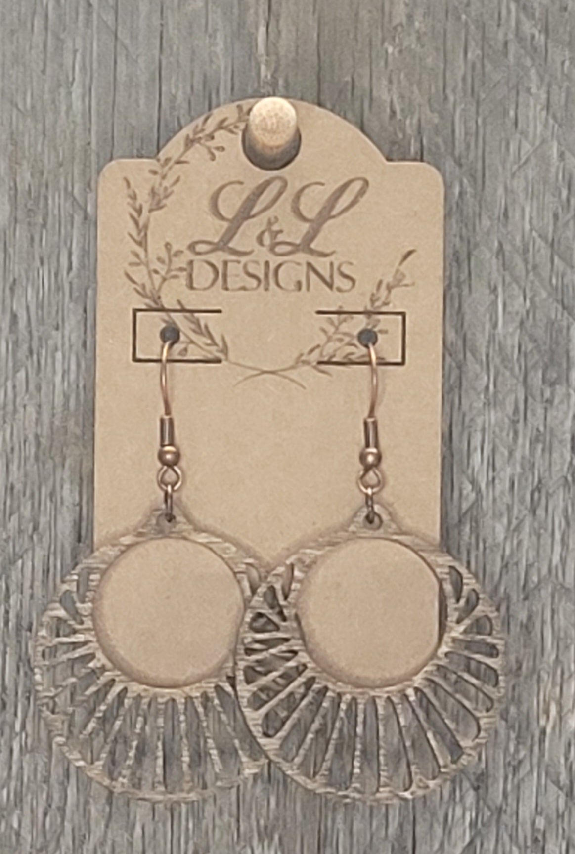 Circular sunburst wood earrings with radiating rays and solid center displayed on L&L Designs branded card against weathered wood background.