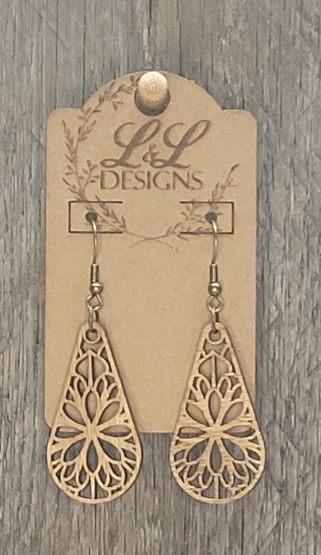 Full view of floral mandala teardrop wood earrings with intricate laser-cut design displayed on L&L Designs branded card against weathered wood background