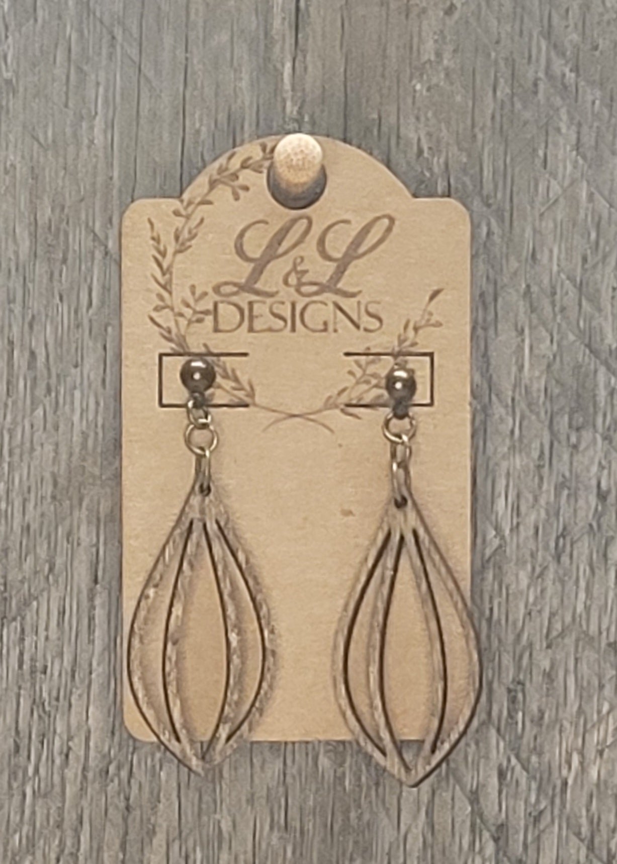 Multi-layered teardrop wood earrings with dimensional cutout design displayed on L&L Designs branded card against weathered wood background.