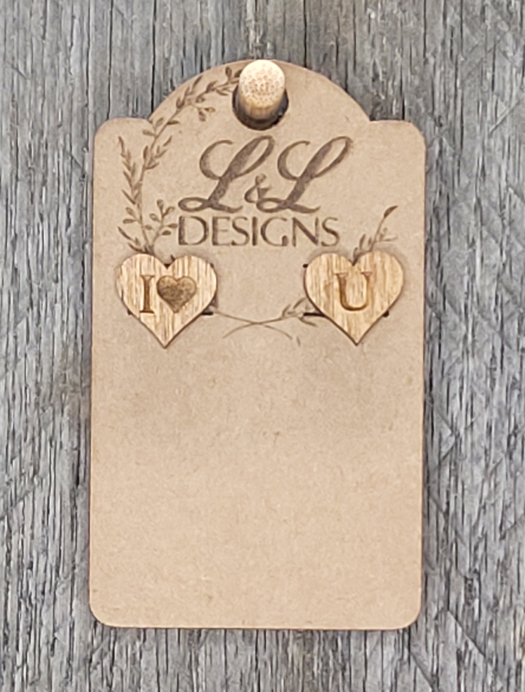 Heart-shaped wood stud earrings with 'I ♥ U' engraved message displayed on L&L Designs branded card against weathered wood background.